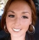 Smiling woman with hoop earrings and brown hair.
