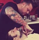 Barber carefully shaving a client's beard in a barbershop.