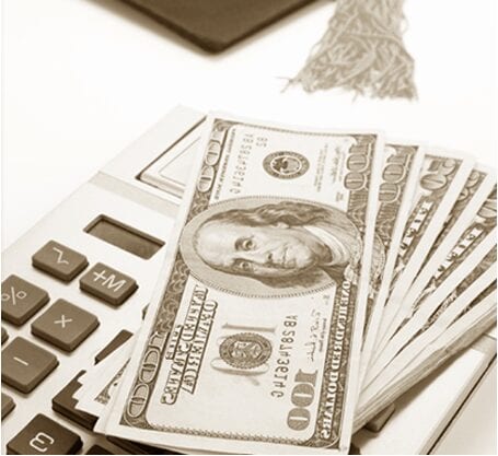 A stack of one-hundred dollar bills on top of a white calculator